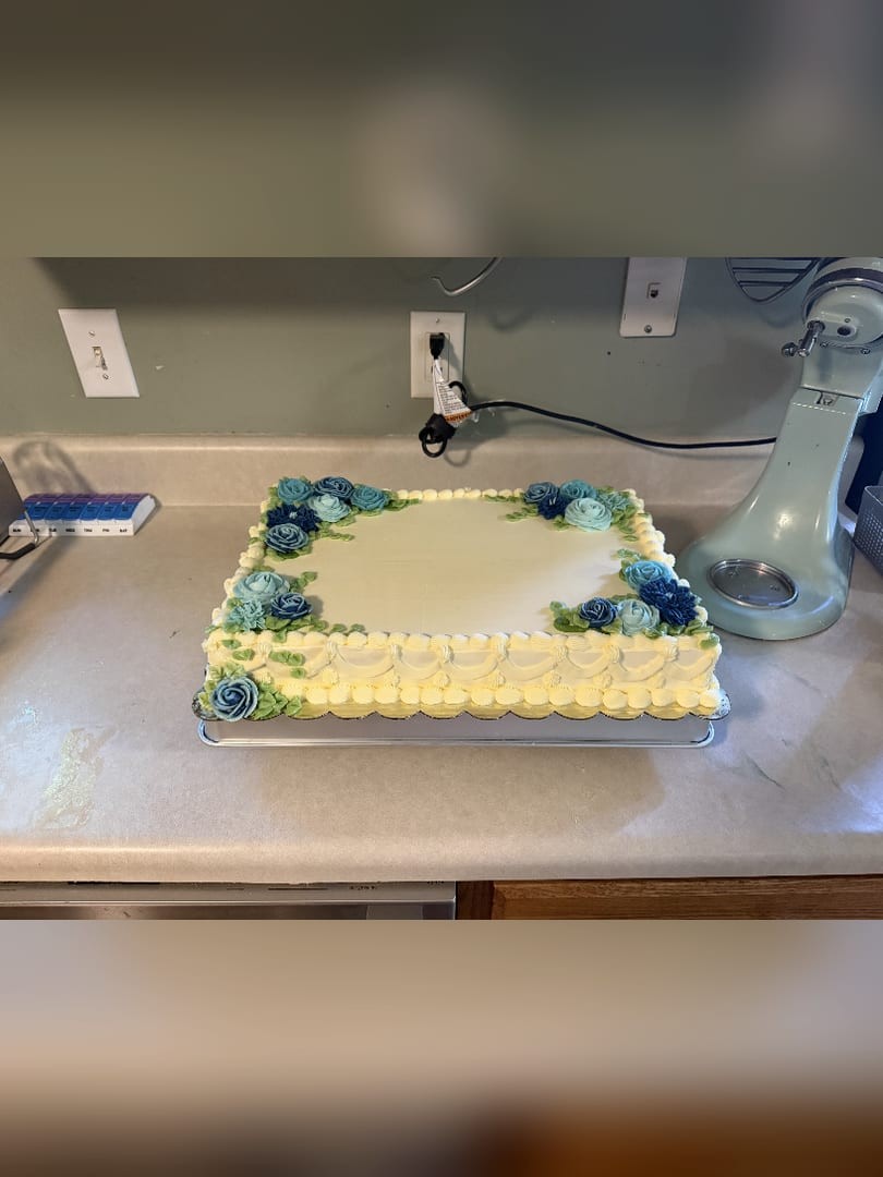 Sheet cake with blue buttercream flowers along the corners and edges