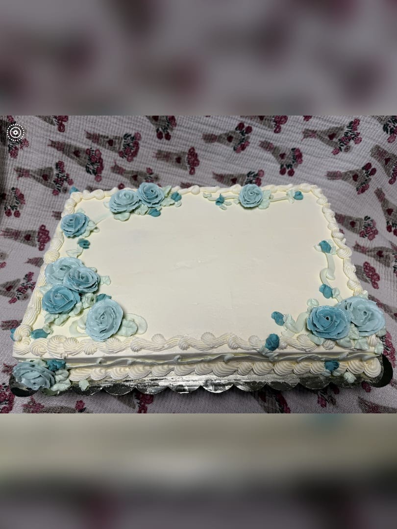 White sheet cake decorated with blue buttercream roses