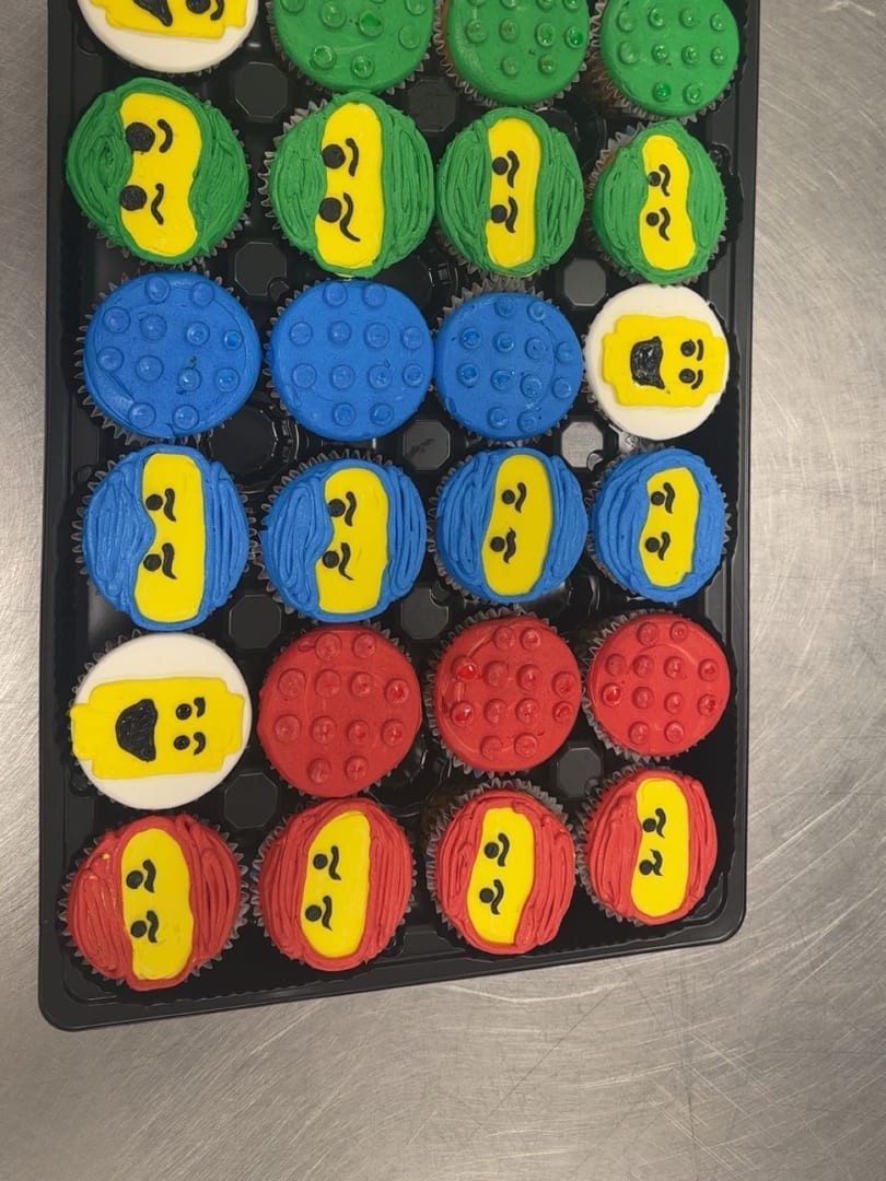 A tray of cupcakes decorated with ninja faces in yellow, red, blue, and green
