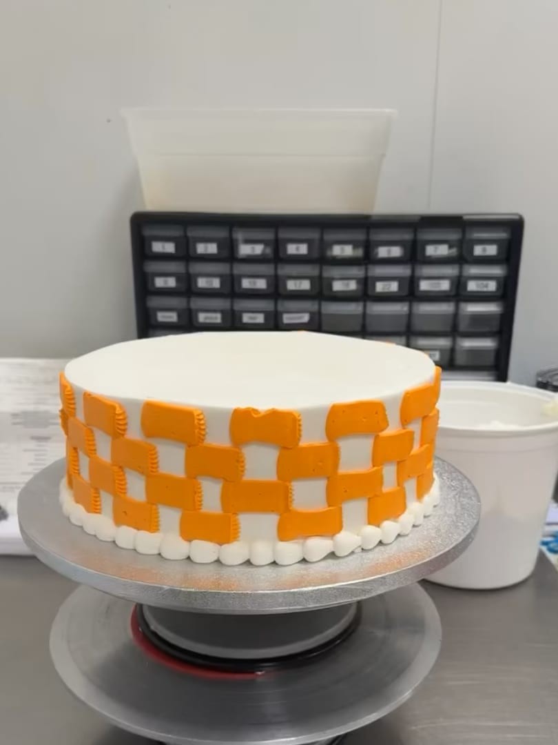Round white cake with an orange checkerboard pattern
