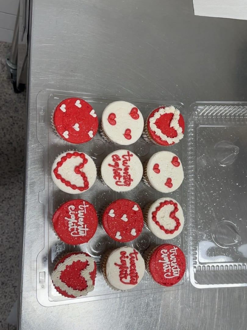 Twelve red and white cupcakes decorated with hearts