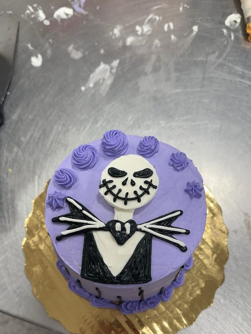 Purple round cake decorated with a pale skeleton in a pinstriped suit