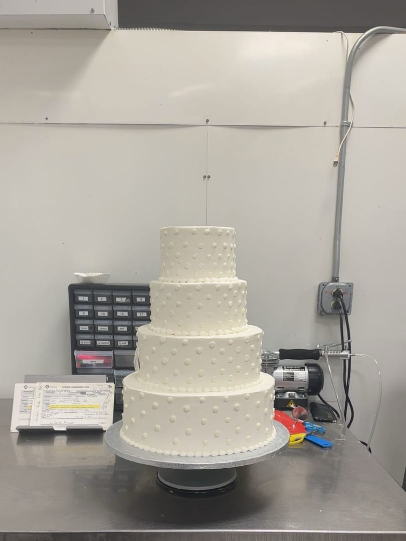 Four-tier white textured cake on a turntable