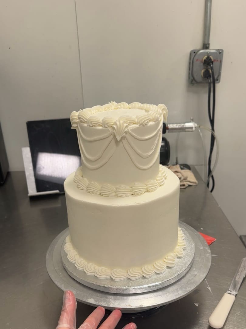 Two-tier ivory cake with scalloped piped swags