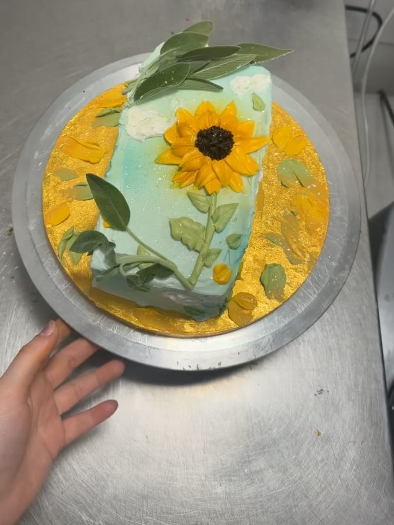 Cake decorated with a painted sunflower and golden leaves
