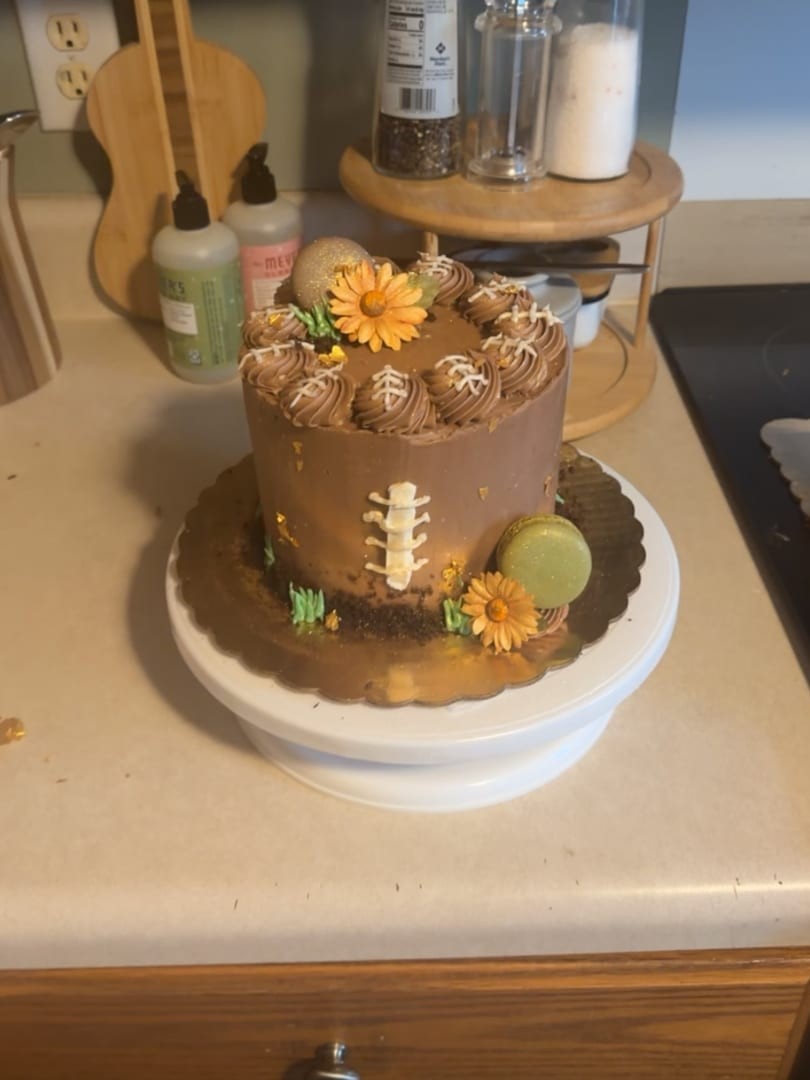 Chocolate buttercream cake topped with orange flowers and a football-laces detail