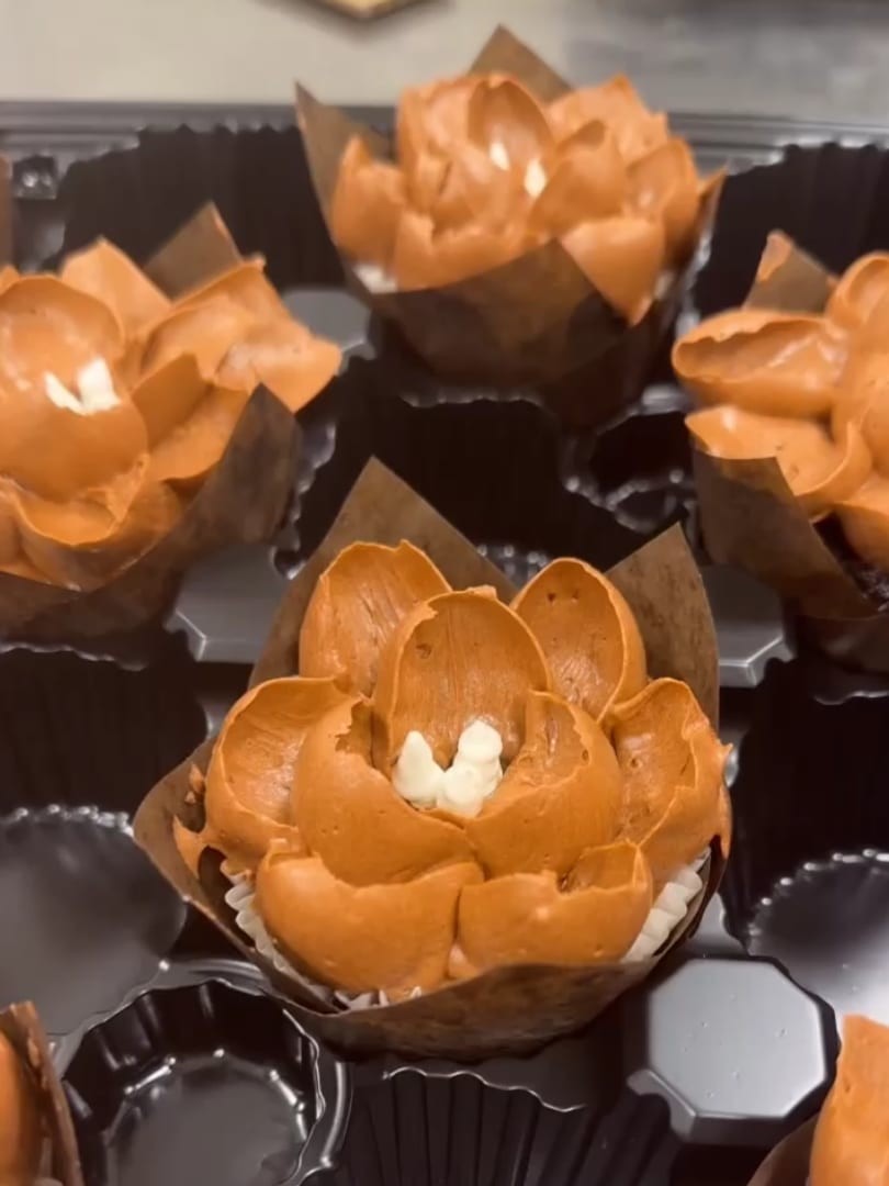 Close-up of orange lotus-style frosted cupcakes