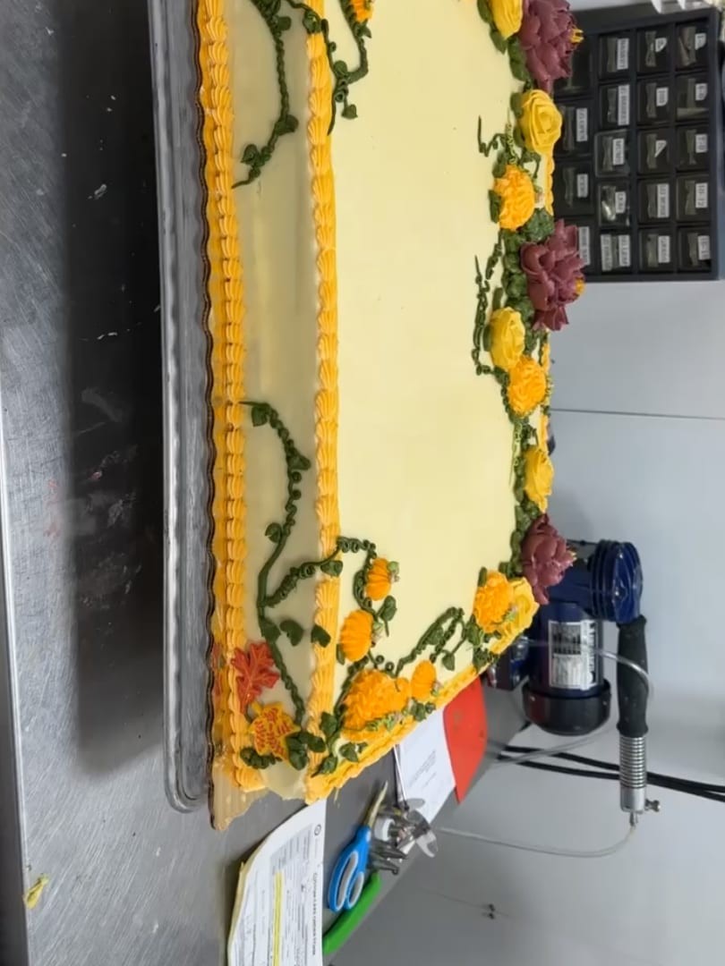 Sheet cake bordered with yellow and orange flowers and green vines